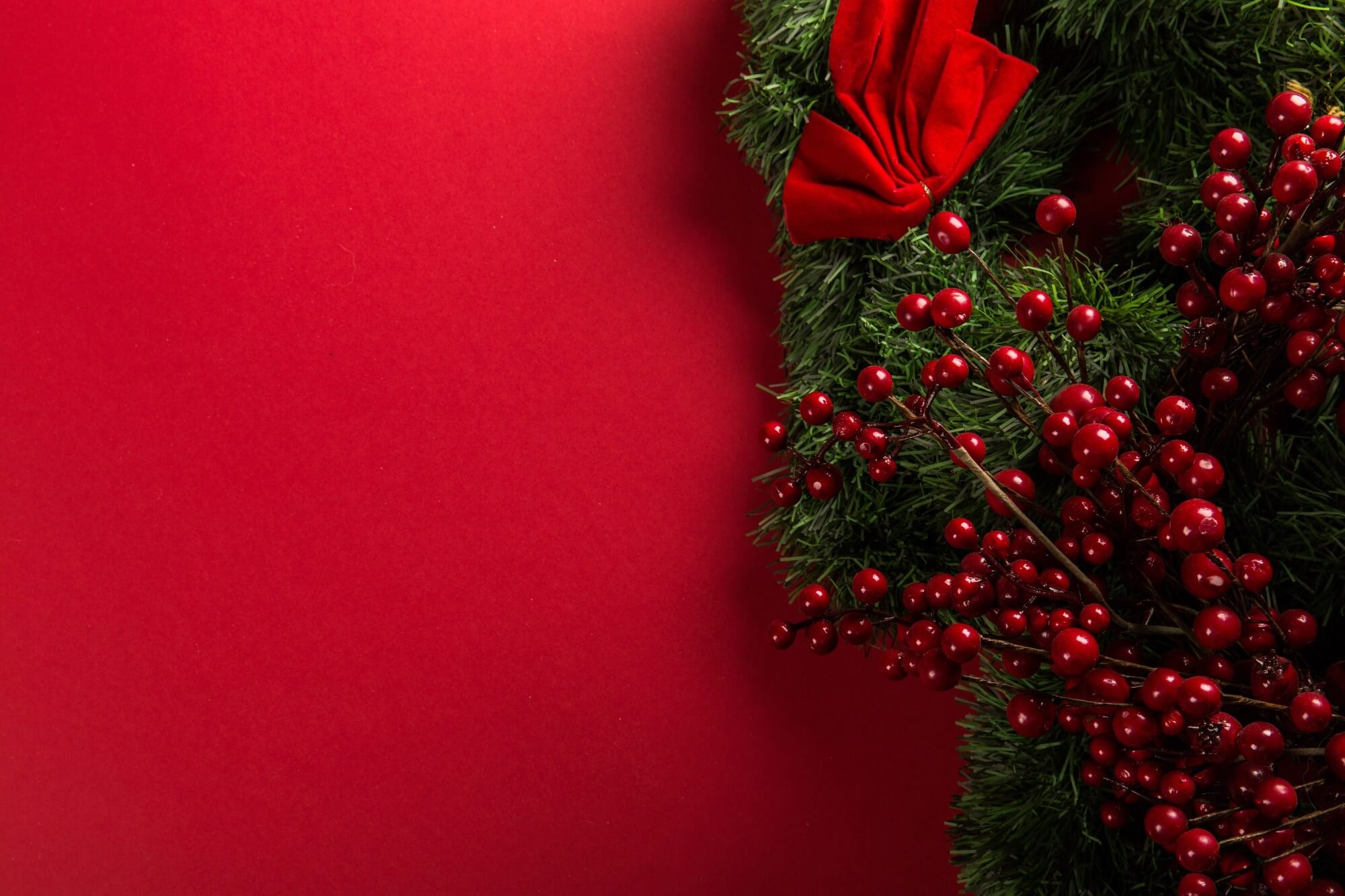 Christmas wreath with ribbons and berries on a deep red background